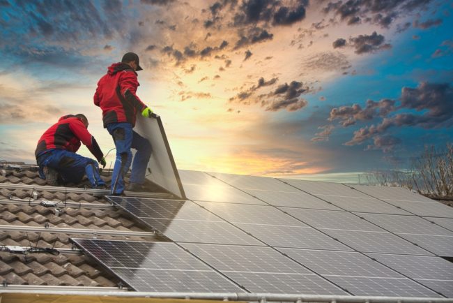 workman installing solar panels on a roof