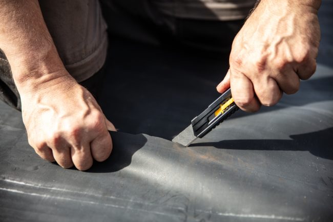 A,Craftsman,Cuts,A,Rubber,Sheet,Apart,With,A,Cutter